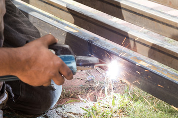 Closeup of worker welding auto gate arm onto metal gate