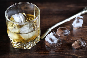 Whiskey in a glass and pieces of ice on a wood