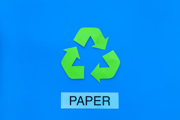 Types of matherial for reycle and reuse. Printed word paper near eco symbol recycle arrows on blue...