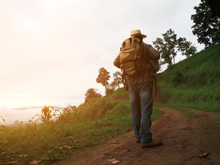 silhouette of travel man with backpack walking on mountain trail at morning sunrise