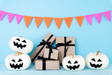 White ghost pumpkin with gift box on sky blue background. halloween concept.