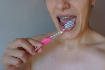 woman brushing her teeth with braces