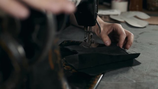 Sewing process of the leather shoes production factory bag belt. Man's hands behind sewing. Leather workshop handmade diy shoemaker