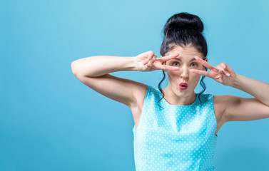 Young woman giving the peace sign on a solid background