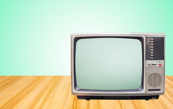 Retro old television receiver on beside table front gradient green wall background.