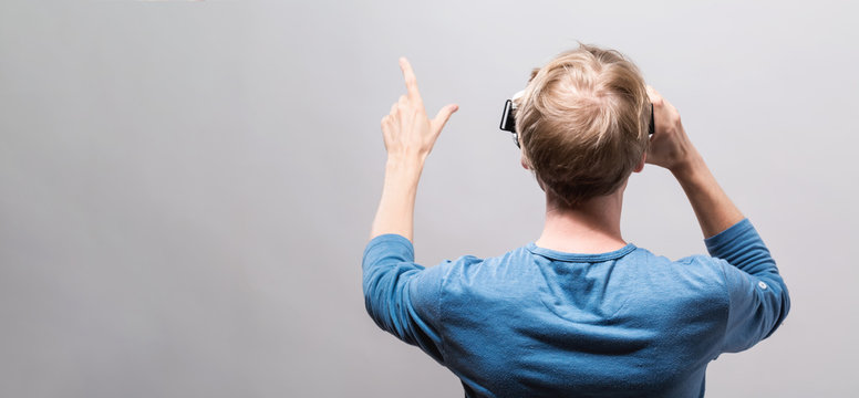 Young Man Using A Virtual Reality Headset From Behind