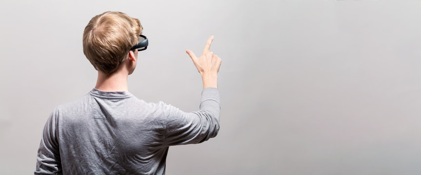 Young man using a virtual reality headset from behind - Powered by Adobe