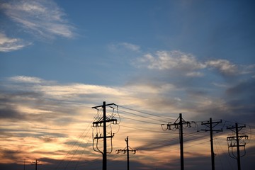 Sunset over a row of utility poles and high voltage overhead power lines in Wyoming / USA.	