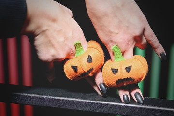 female hands with black manicure playing with puppets in form pumpkins for Halloween on fingers