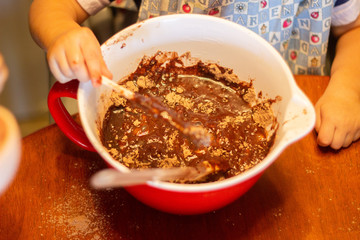Toddler stirs chocolate fudge brownie mix
