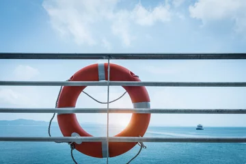 Poster Im Rahmen orange lifebuoy ring hanging on ferry boat with ocean background © mmmx