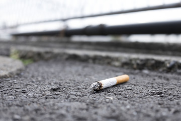 Tossed cigarette which goes out itself left on the asphalt.