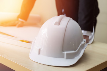 Engineer safety white helmet on work table and manager looking in blueprint for planing...