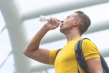 Fototapeta na wymiar Strong sport man in yellow is drink water in city outdoor