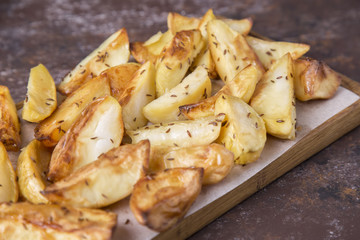 Tasty fried potato with cumin on wooden board