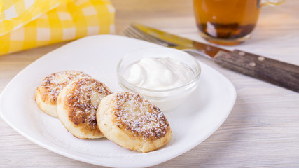 Cottage cheese pancakes with  sour cream and powdered sugar.  Copyspace
