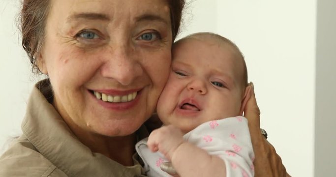 Grandmother Holding Newborn Baby Granddaughter indoores white background