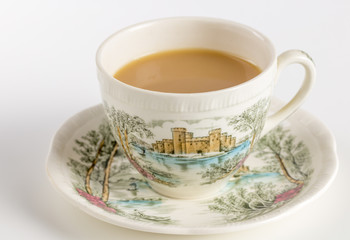 Teacup with tea and saucer decorated with English castle scene with tea drink - antique cup and saucer