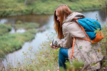 Girl traveler with red long hair sitting and looking at wild nature © Galina Zhigalova