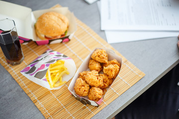 Chicken nuggets with burger and french potatoes on the desk with business papers