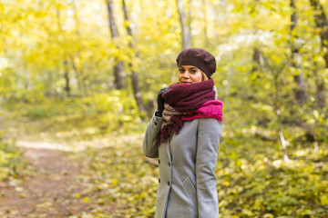 Fall, nature and people concept - Young beautiful woman in grey coat standing in autumn park