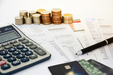 close up of a credit cards with credit card statements, pen, stack of coins and calculator on white...