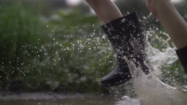 close-up of feet running through puddles, slow motion, splash