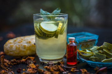 Close up of organic face pack of cucumber with aloe vera gel and rose oil on wooden surface in a glass container for Sunburns and tans with raw cucumber or kheera and rose leaves with aloevera leaf.
