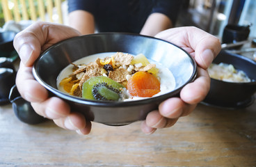 Man Holding muesli bowl, eating breakfast cereals with nuts, pumpkin seeds, oats, dried fruit and yogurt, healthy concept