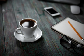 A cup of coffee in the workplace on a wooden table.