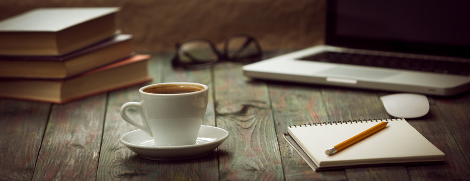 A cup of coffee in the workplace on a wooden table.