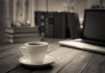 A cup of coffee in the workplace on a wooden table.