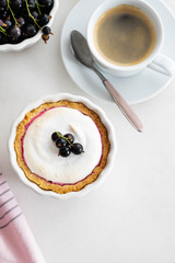 Delicious tart decorated with burned merengue and berries, served in white composition, with copy space. Top view.