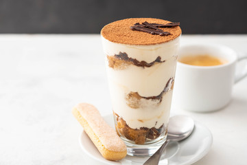 Tiramisu in a glass with coffee beans on white background. Copy space.