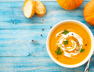 Pumpkin and carrot soup with parsley on blue background Top view.