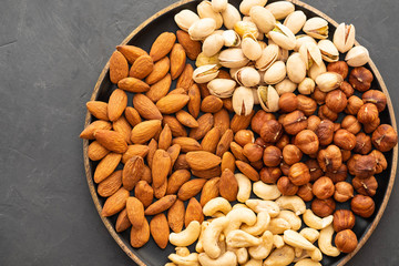 Assorted nuts in bowls on a black background. Copy space.