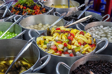 Large pots full of traditional Asian dessert jellies, colorful fruit, and gelatinous sweets served in the street in Vietnam