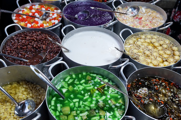 Large pots full of traditional Asian dessert jellies, sweet beans, and gelatinous sweets served in the street in Vietnam