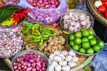 A basket tray filled with aromatic ingredients used in South East Asian cuisine such as limes, chilis, garlic, and ginger