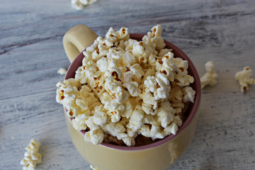 A bowl of delicious caramel popcorn on a white wooden background