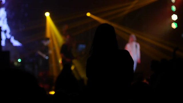 Girl fan silhouette raise hands enjoying music concert in flashing lumiere