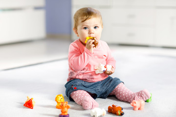 Adorable baby girl playing with domestic toy pets like cow, horse, sheep, dog and wild animals like giraffe, elephant and monkey. Happy healthy child having fun with colorful different toys at home