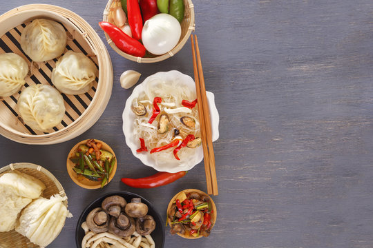 Dishes of Chinese cuisine in assortment. Steam dumplings, noodles, salads, vegetables, mushrooms, seafood. Top view. Copy space