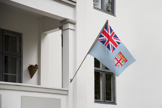 Fiji flag.  Fiji flag hanging on a pole in front of the house. National flag of waving on a home displaying on a pole on a front door of a building. Flag raised at a full staff.