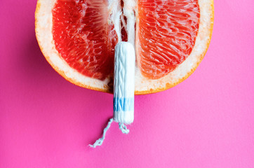 tampon and grapefruit on a pink background. Concept Vagina symbol and menstruation