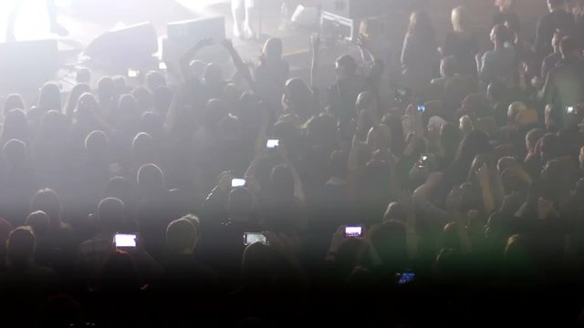 Crowd people shooting video by phones at concert stroboscope lumiere lights