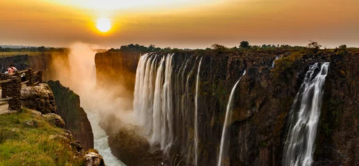 Cercles muraux Panoramique Victoria falls sunset panorama with orange sun and tourists
