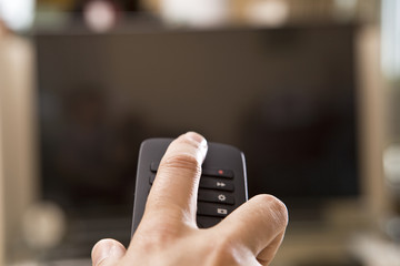 Yong man hand with remote changes channels