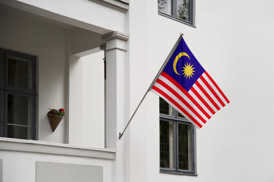 Malaysia flag.  Malaysia flag hanging on a pole in front of the house. National flag of waving on a home displaying on a pole on a front door of a building. Flag raised at a full staff.