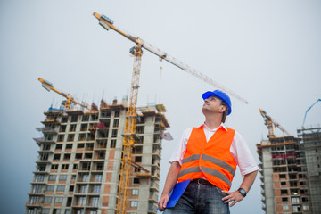 Proud architect on a construction site with buildings and cranes in the background